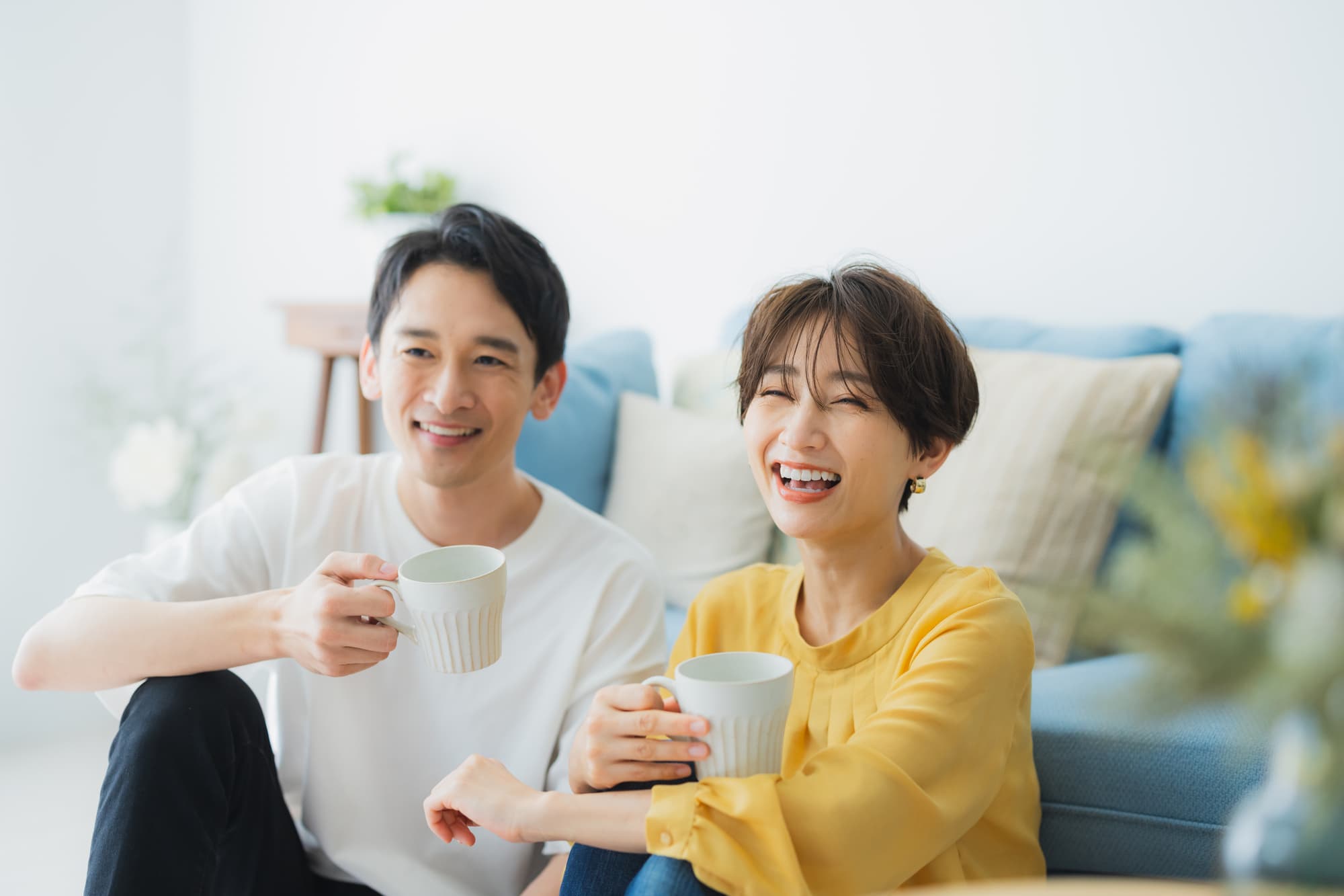 笑顔でコーヒーカップ片手に寛ぐ夫婦