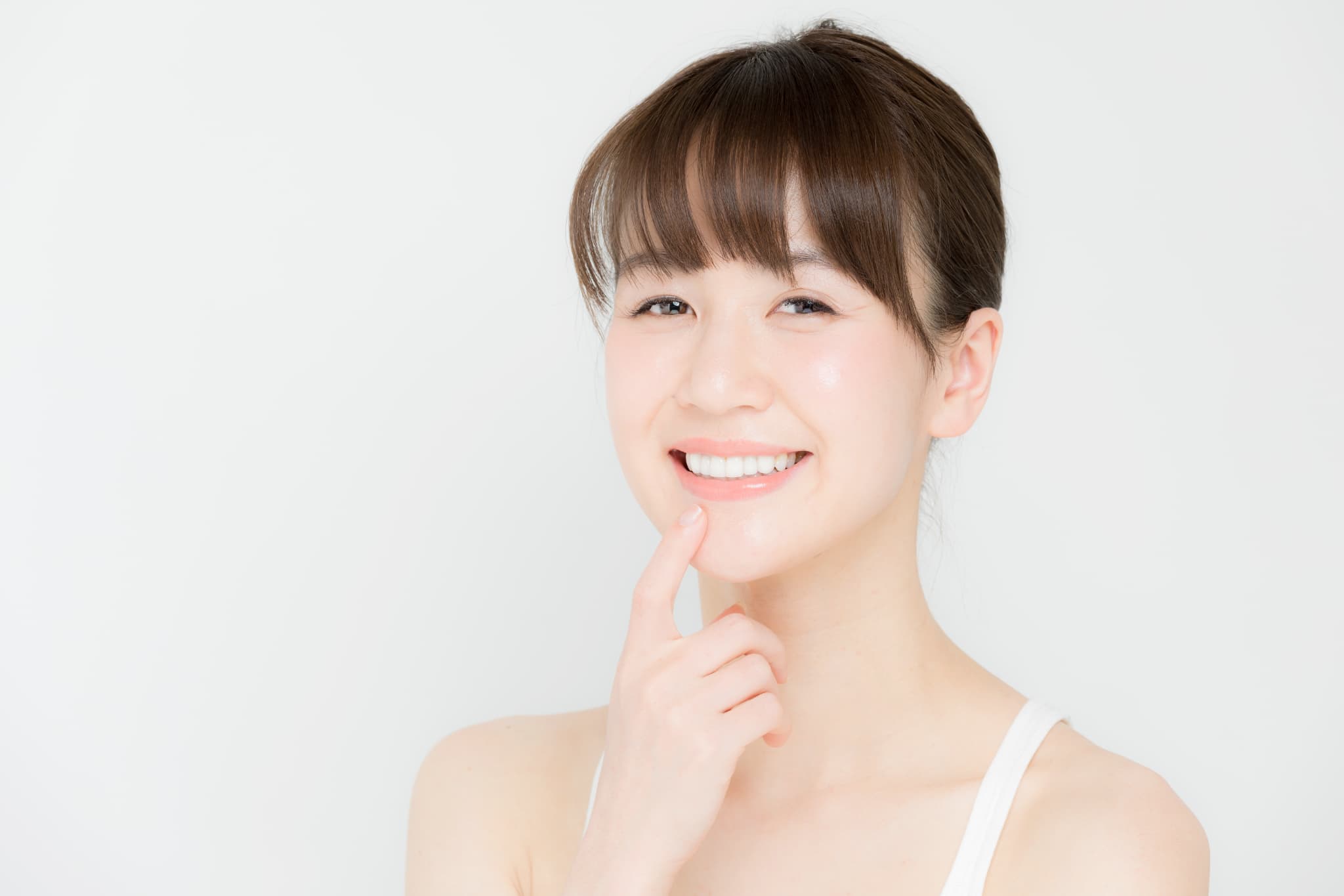 白いきれいな歯を指さし微笑む女性