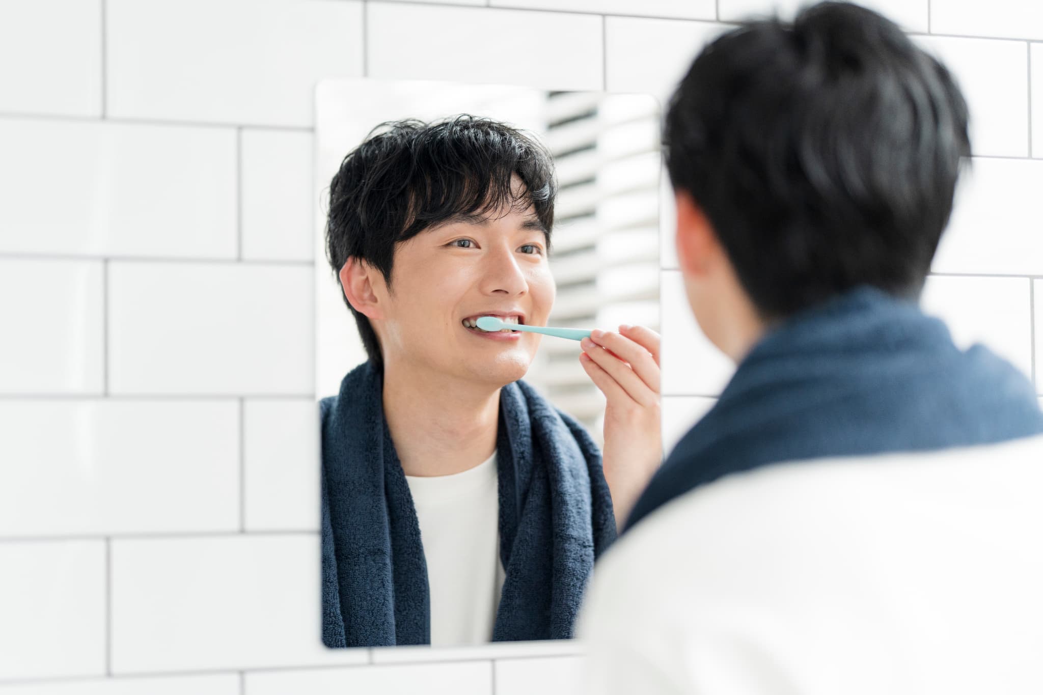 鏡を見ながらしっかりと歯磨きをする男性