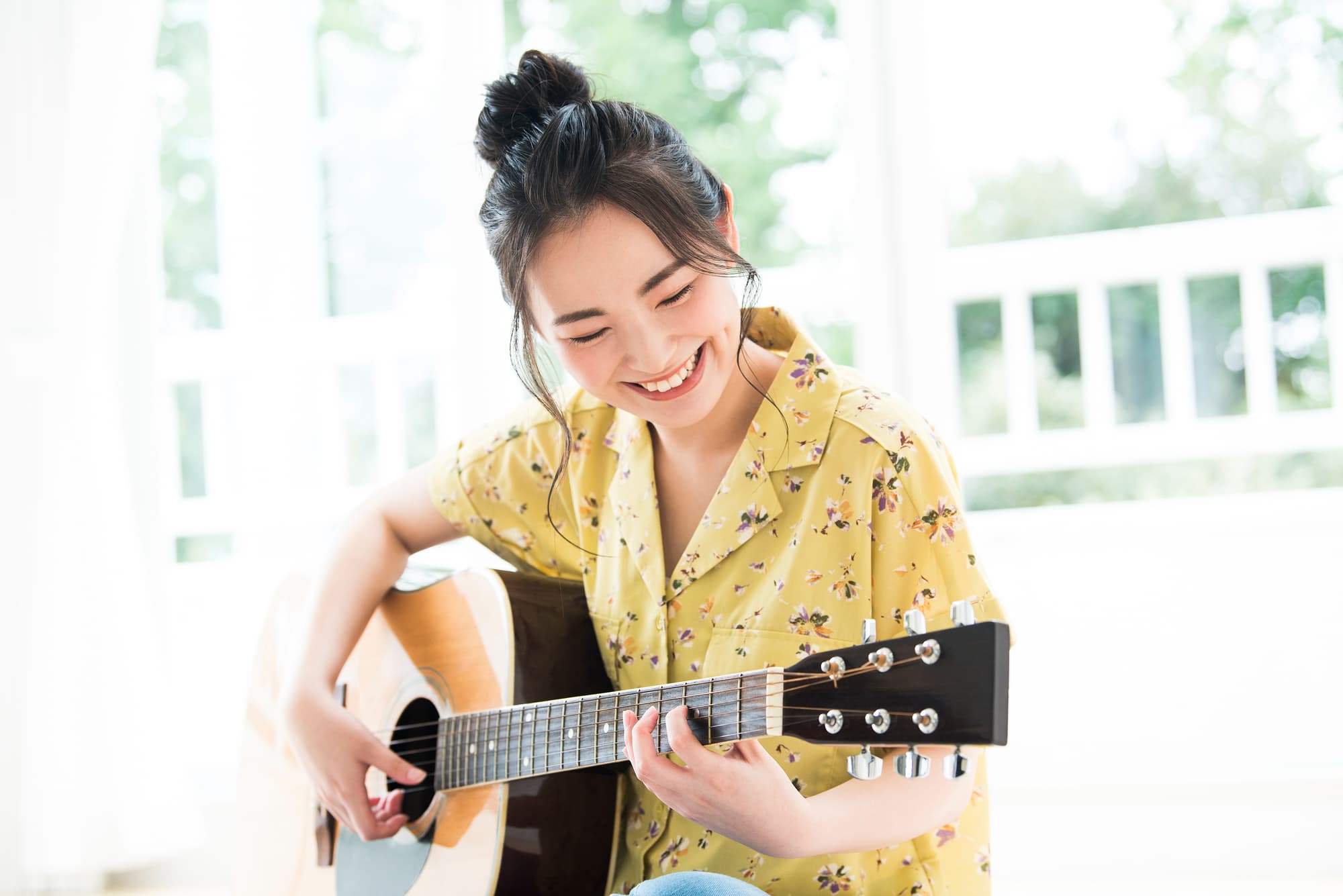 リビングでギターの練習をする笑顔の女性