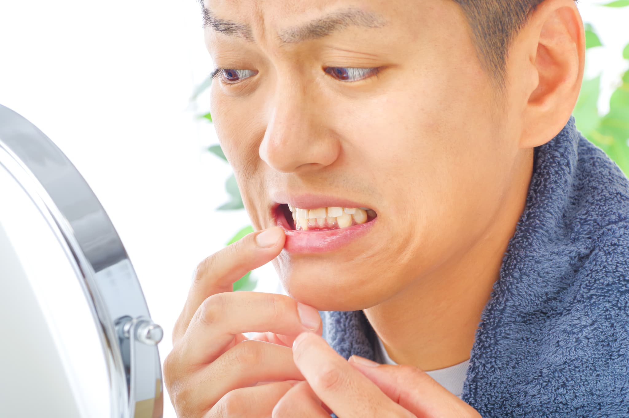 鏡で歯ぐきをチェックする男性