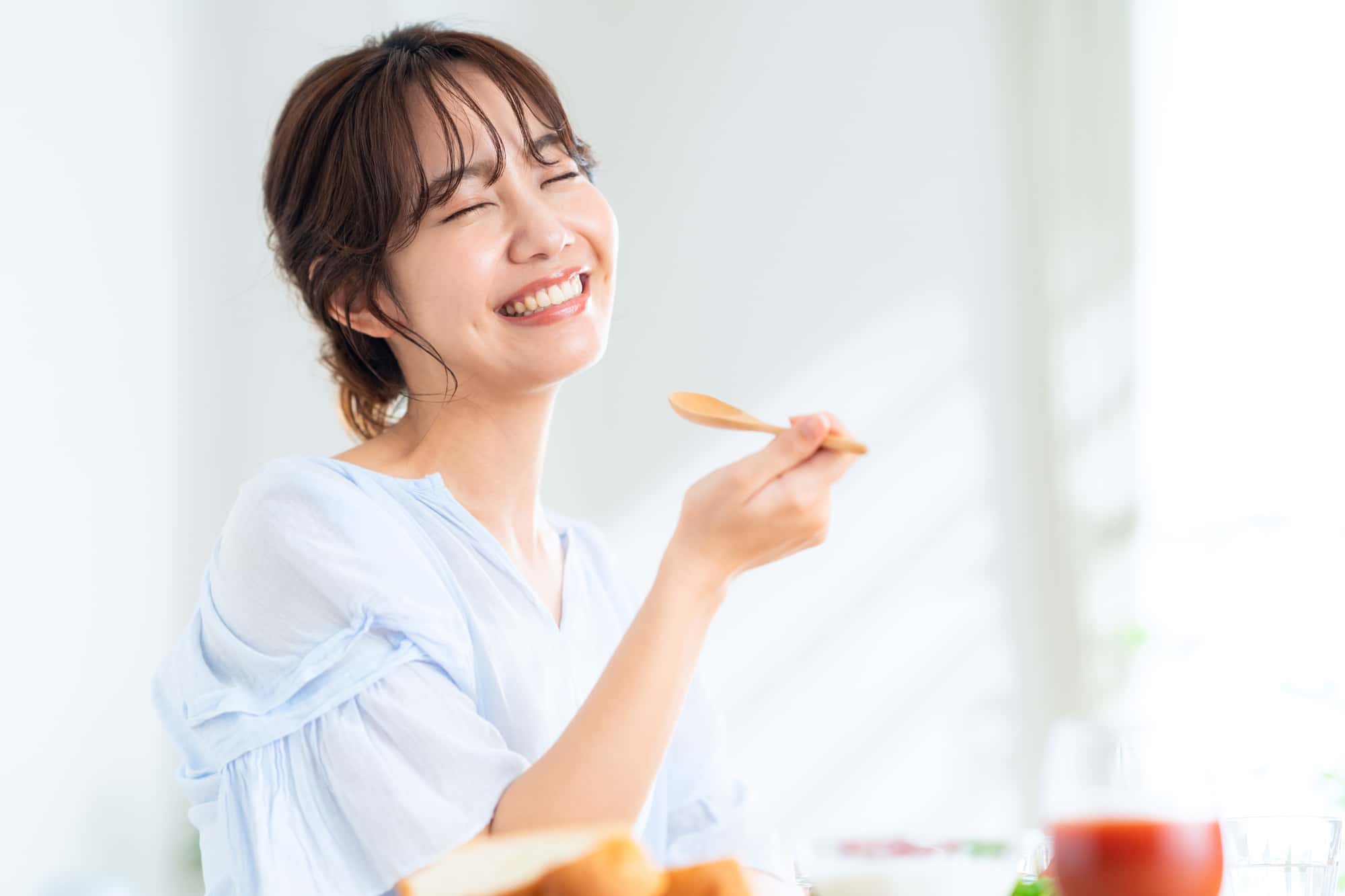 ワイヤー矯正で美しい歯ならびになった女性が美味しそうに食事をしているイメージ