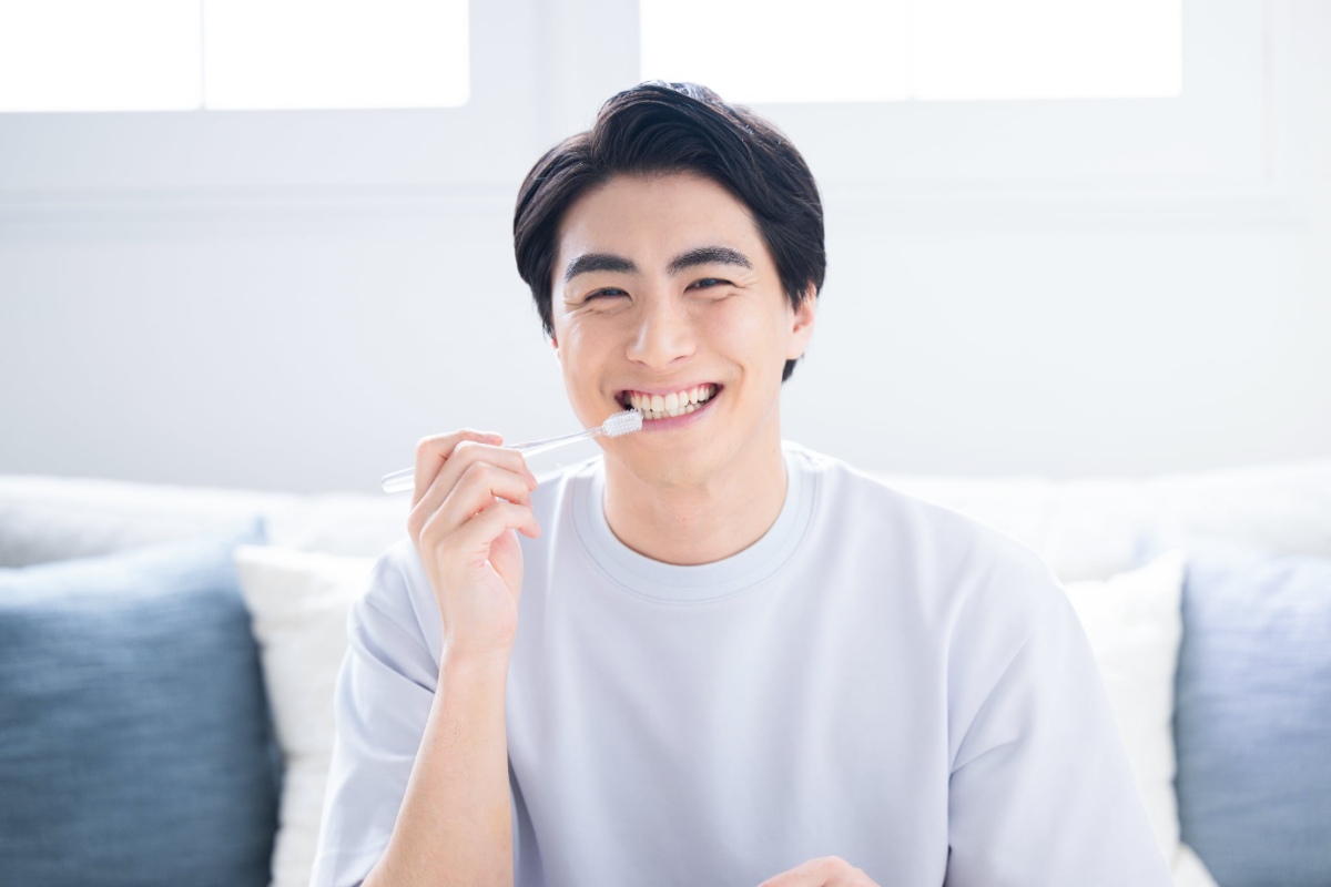 ソファに座って笑顔で歯磨きをしている男性