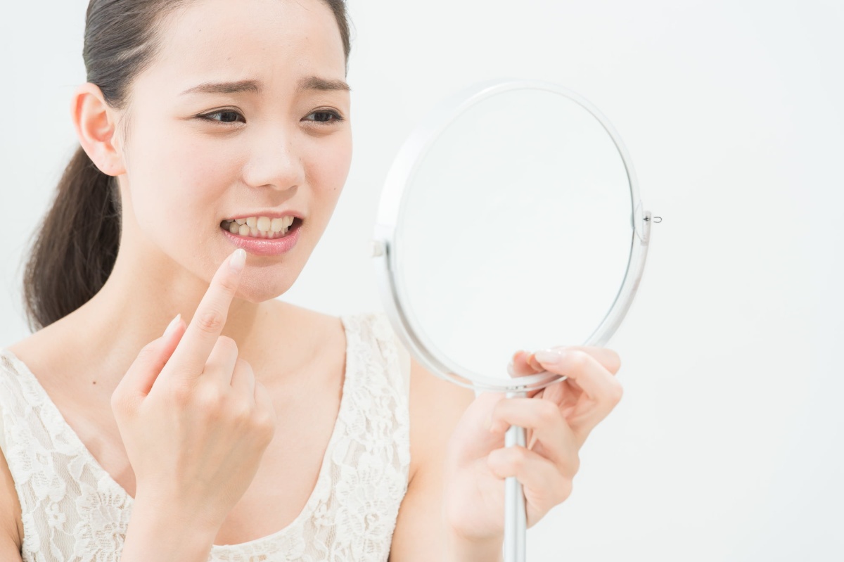 ホワイトニングした歯を鏡で見て後悔している女性